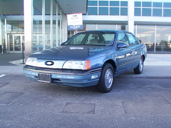 blue sedan parked in front of a modern building