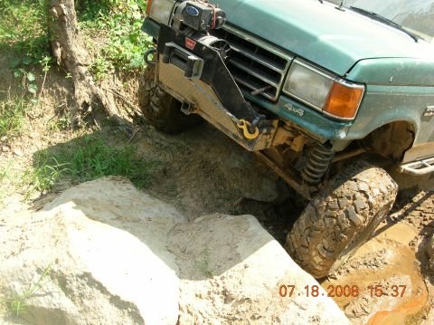 1991 Ford F-150 - 1991 Ford F-150 tackling a challenging off-road obstacle with large tires and suspension articulation.