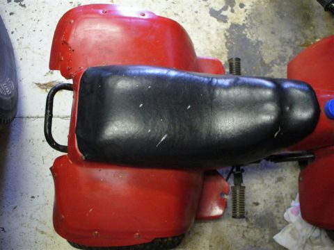 1988 Ford Bronco - A close-up view of a red plastic component with a black seat, possibly from a recreational vehicle or toy.