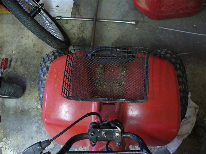 Red ATV with a black wire basket on the rear fender and a lug wrench on the ground