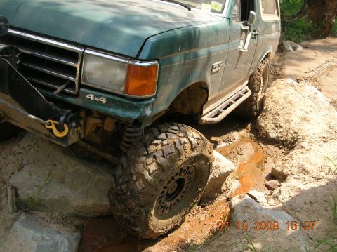 1991 Ford F-150 - This Ford Bronco is shown off-roading on a challenging, rocky, and muddy course.