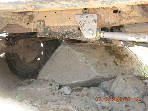 1991 Ford F-150 - The undercarriage of an off-road vehicle is shown navigating over large rocks, with a component labeled 'CAGE' clearly visible.