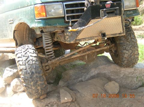 1991 Ford F-150 - Front view of a green Ford truck with off-road modifications, including a winch and lifted suspension, on a rocky terrain.