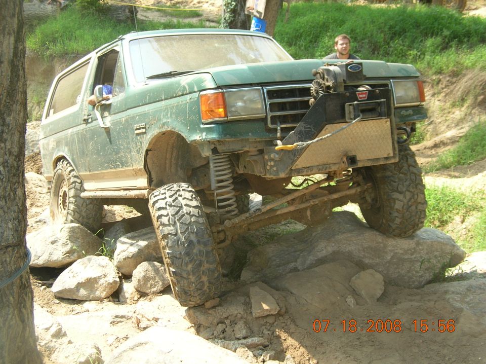Green 1991 Ford Bronco off-roading over rocks