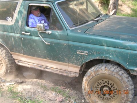 1991 Ford F-150 - Ford Bronco navigating rough terrain, kicking up dust.