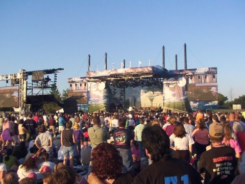 1998 Ford Taurus - A large crowd gathers for an outdoor concert, with a prominent stage set up in the background.