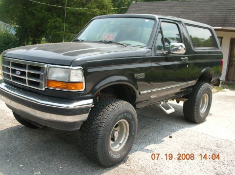 1991 Ford F-150 - A black Ford Bronco is parked outside a building, with a 'For Sale' sign visible in the windshield.