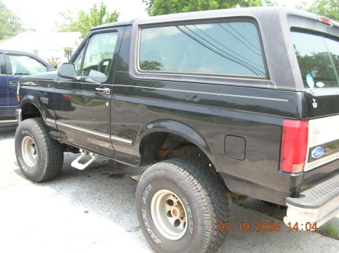 1991 Ford F-150 - Black 1992 Ford Bronco with a white stripe on the rear quarter panel, parked next to another vehicle.