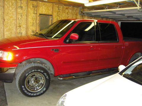 2007 Ford Mustang - Red Ford F-150 pickup truck with F-150 badging, seen from the side in a garage.