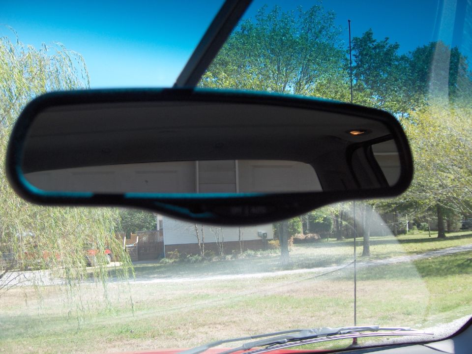 Interior rearview mirror reflecting a garage and trees