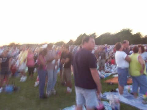 1998 Ford Taurus - A large group of people are seen from the side at an outdoor gathering with a bright sky overhead.