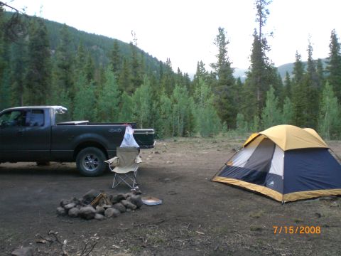 2004 Ford F-150 - A campsite scene with a truck, tent, and fire pit is set up in a forest.