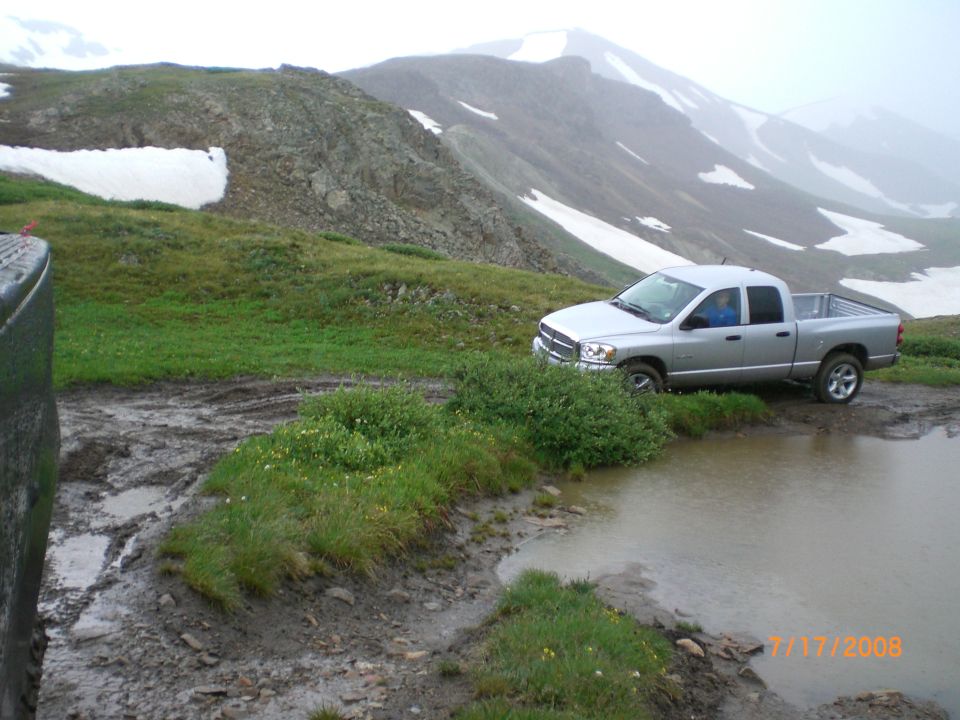 Silver pickup truck parked on muddy mountain road near puddle. Date stamp 7/17/2008