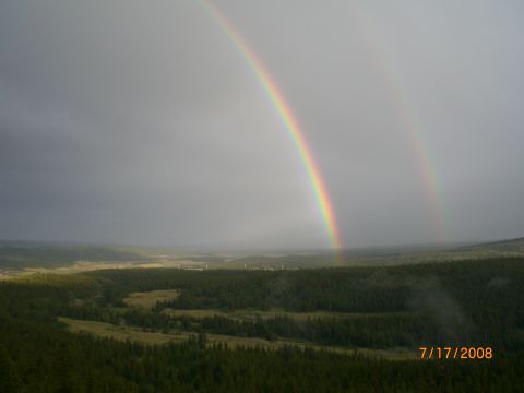 2004 Ford F-150 - A double rainbow appears after a rain shower over a dense forest and rolling hills.
