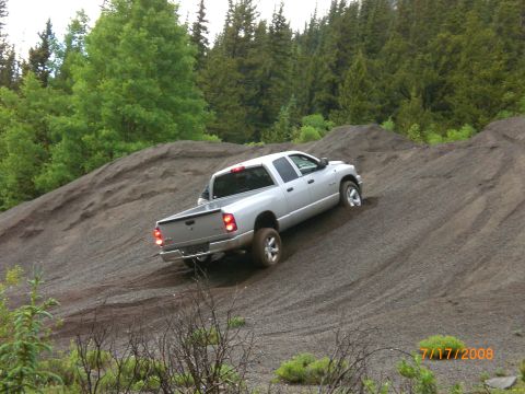2004 Ford F-150 - A silver pickup truck navigates a steep gravel incline surrounded by trees.