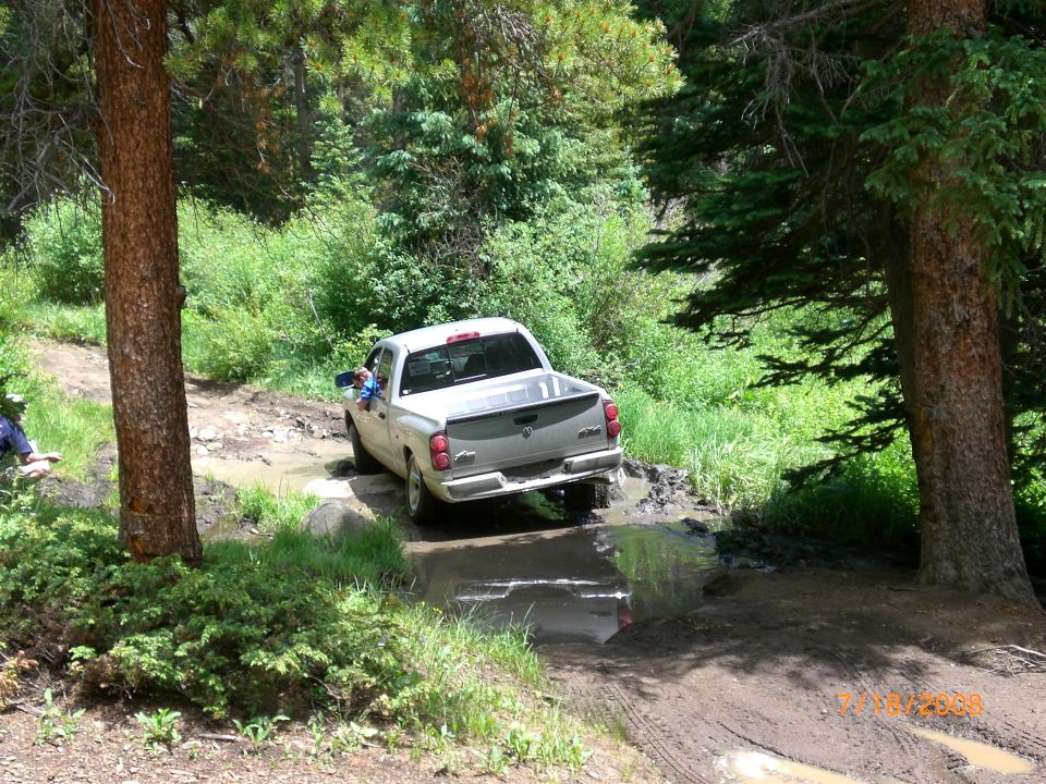White pickup truck navigating a muddy trail