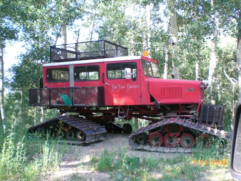 2004 Ford F-150 - A vintage red tracked vehicle, identified as 'San Juan Snocats', sits in a forest clearing.
