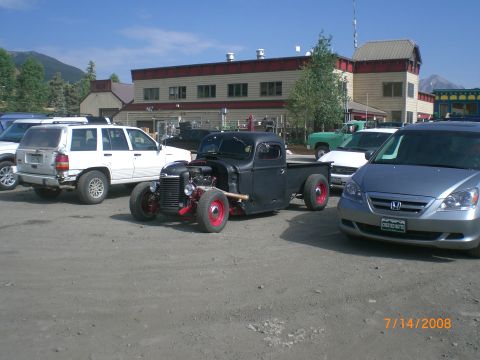 2004 Ford F-150 - A custom black hot rod pickup truck is parked among other vehicles on a sunny day.