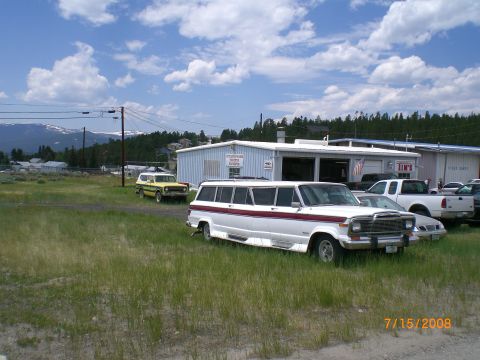 2004 Ford F-150 - Extended wheelbase Jeep Grand Wagoneer limousine conversion parked outside a building with other vehicles.