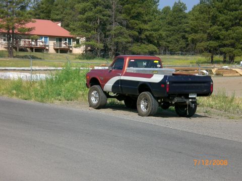 2004 Ford F-150 - A classic pickup truck with a custom paint job and lifted suspension is seen parked on the side of a road.