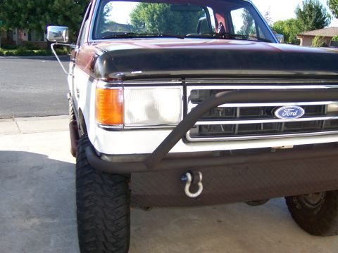 1991 Ford Bronco - Front view of a white Ford truck with a custom bumper and black hood. The grille shows the Ford logo.