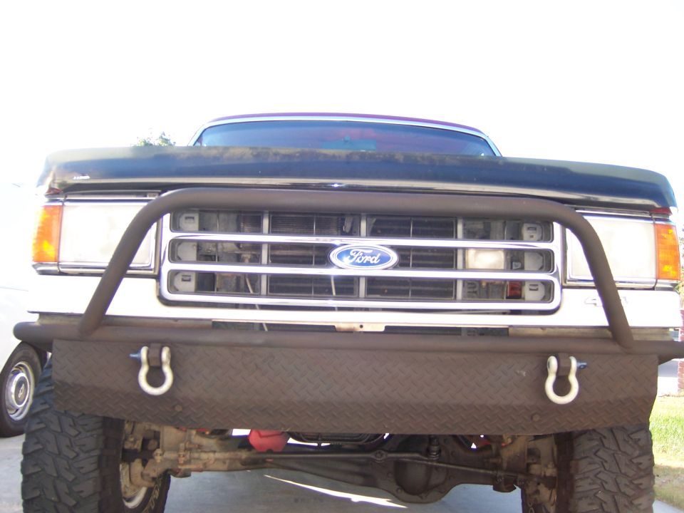 Front view of a dark blue 1992 Ford Bronco with a custom diamond plate bumper and brush guard
