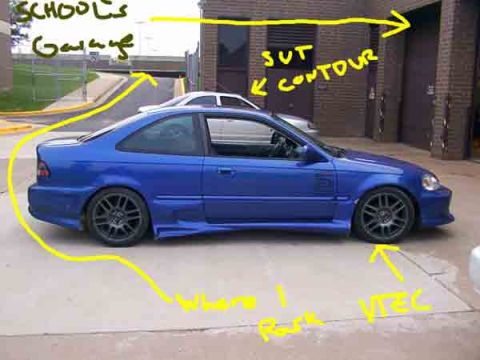 1998 Ford Taurus - A blue coupe is parked in front of a brick building with yellow markings on the image.
