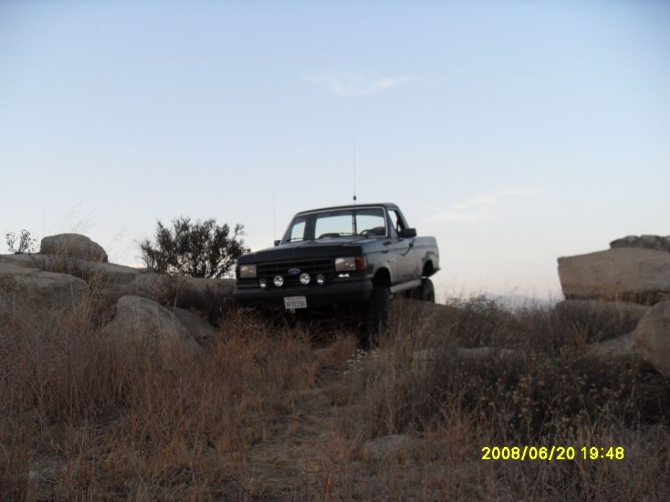 Black 1990 Ford Bronco off-roading on rocky terrain