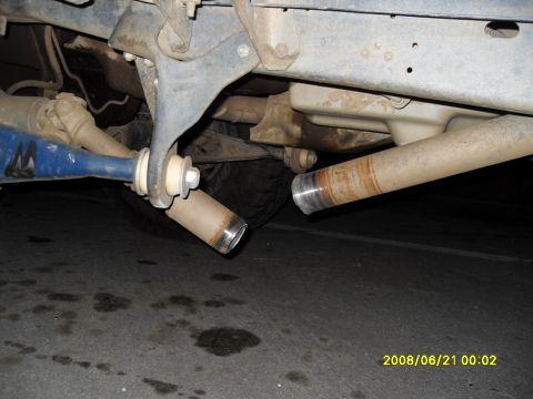 1990 Ford Bronco - The underside of a vehicle shows a damaged exhaust system with two severed pipes. A blue suspension component is visible on the left.