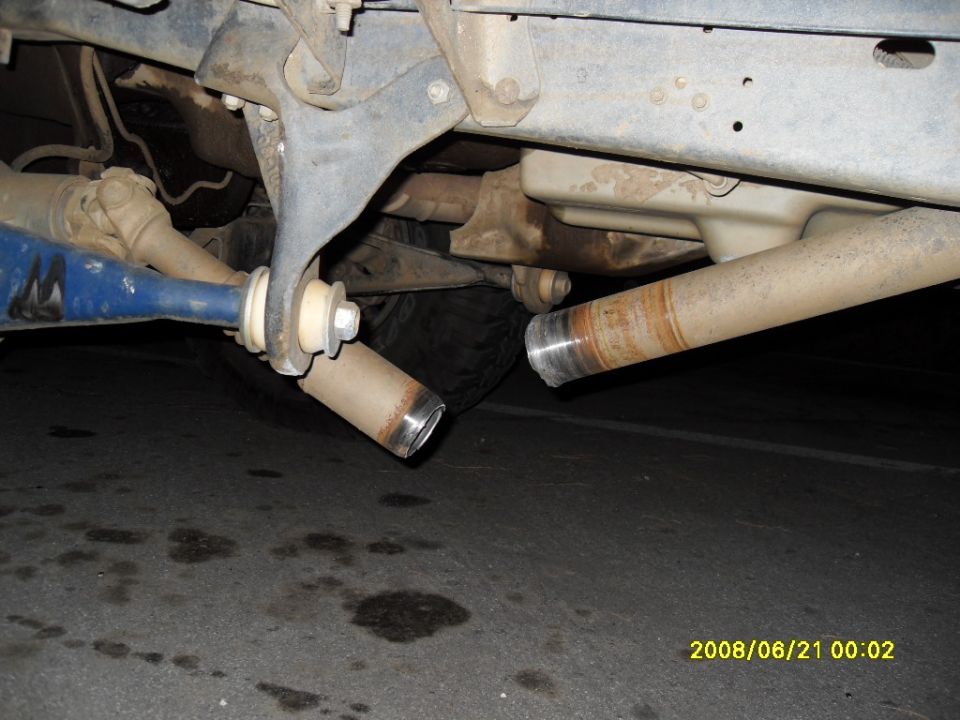 Underside of vehicle showing broken exhaust pipes and blue suspension part.