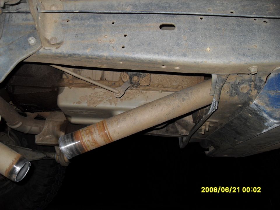 Undercarriage of a vehicle showing exhaust pipes and driveshaft with weld.