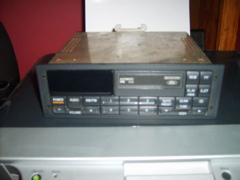1993 Ford Crown Victoria - A close-up view of a vintage Ford car radio with a digital display and numerous buttons. The radio is mounted in a dark gray dashboard.