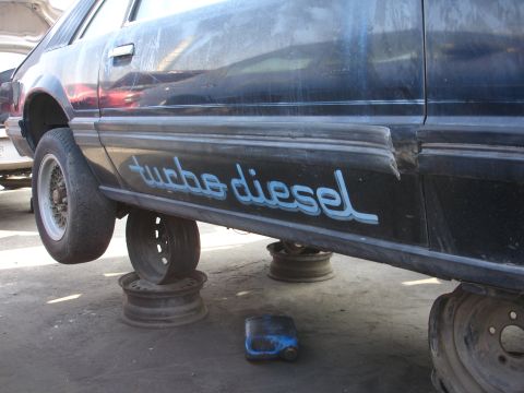 1993 Ford Taurus - Side profile of a dark sedan, elevated for maintenance, displaying text on its lower door panel.