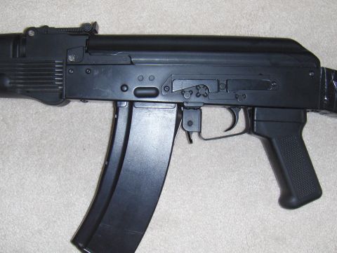 2003 Ford Crown Victoria - A black rifle with a magazine is shown in a close-up side view.