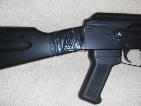 2003 Ford Crown Victoria - Close-up view of an airsoft gun's stock, which appears to be secured with black tape.