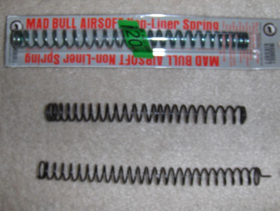 Two airsoft gun springs, one in packaging labeled MAD BULL AIRSOFT Non-Liner Spring