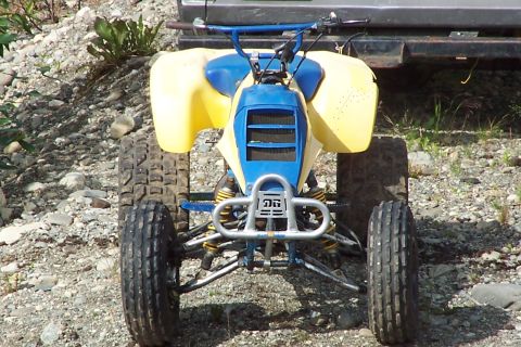 1989 Ford Bronco II - This ATV features a blue front grille and yellow body panels, with a silver bumper and knobby tires.