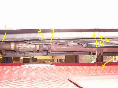 1998 Ford Taurus - The underside of a vehicle is shown on a lift, with yellow markings indicating various parts.