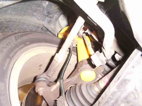 1998 Ford Taurus - Undercarriage view showing suspension parts and a tire, with a visible yellow shock absorber.