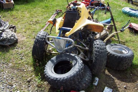 1989 Ford Bronco II - An all-terrain vehicle sits in a grassy area with its tires flat and some parts disassembled.