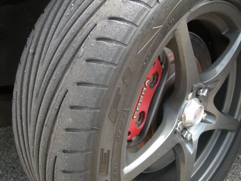 1992 Ford Taurus - Close-up of a worn tire and a red brake caliper with 'Cobra' branding, mounted on a dark gray alloy wheel.