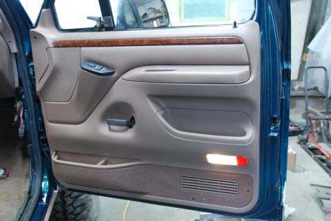1996 Ford Bronco - Interior view of a vehicle's door panel, showing tan upholstery and wood trim details.