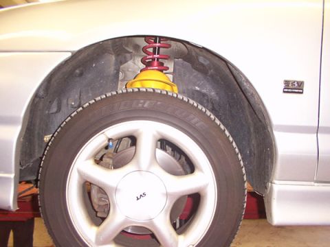 1998 Ford Taurus - Close-up of the front wheel and suspension assembly on a 1998 Ford Taurus.