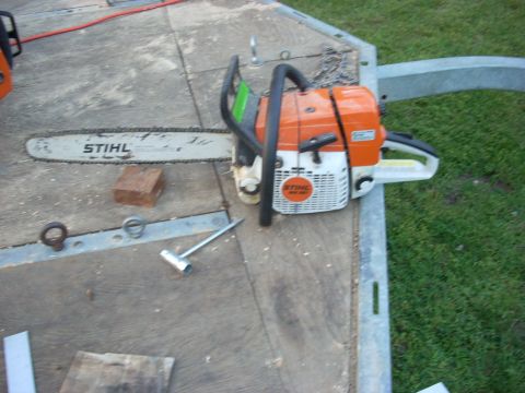 2000 Chevrolet Tahoe - A Stihl chainsaw rests on a wooden trailer deck next to a tool and a small block.