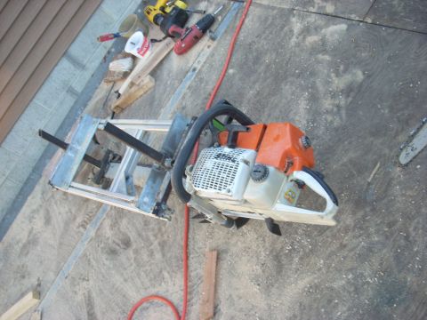 2000 Chevrolet Tahoe - A chainsaw is mounted on a milling jig, with power tools and construction materials scattered around.