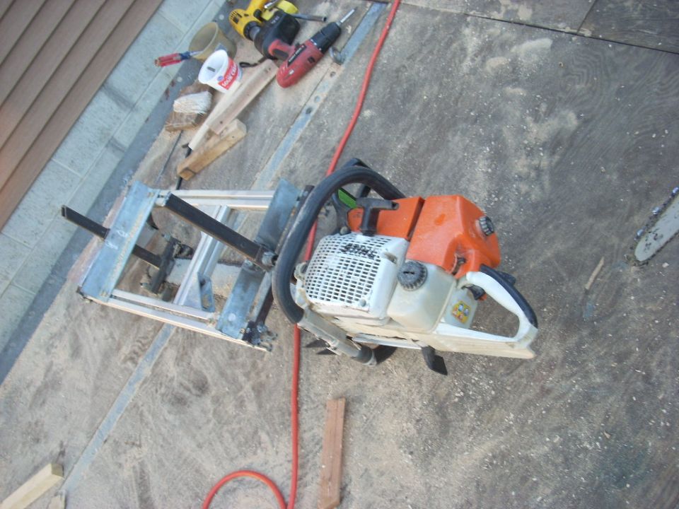 Chainsaw attached to a metal milling jig with a red cord and power tools in the background