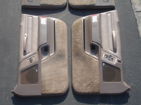 1993 Ford Taurus - Pair of interior car door panels, likely from a sedan, shown laid out on asphalt.