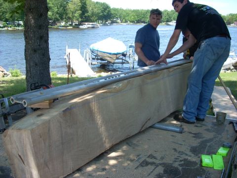 2000 Chevrolet Tahoe - Men are working on a large wooden beam next to a lake with a boat dock in the background.