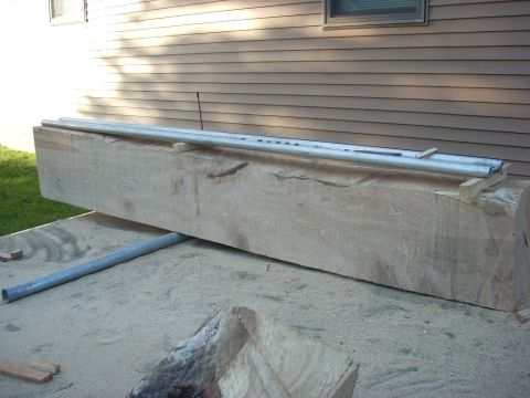 2000 Chevrolet Tahoe - A large wooden beam is supported by metal pipes and rests on a sandy surface next to a building.