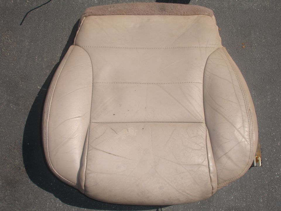 Beige leather car seat with visible wear and tear, showing stitching and textured panels